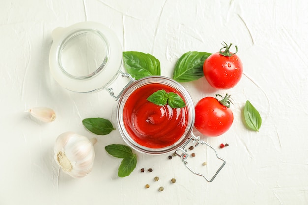 Flache Komposition mit frischen Tomaten, Basilikum, Pfeffer, Knoblauch und Sauce im Glasraum für Text und Draufsicht