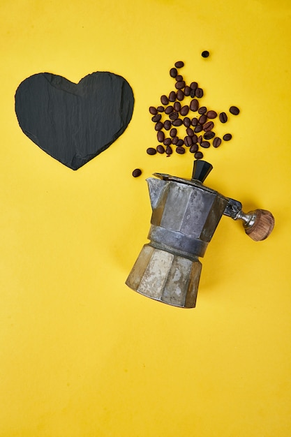 Flache Lage der Kaffeemaschine und der Kaffeebohnen auf gelbem Hintergrund