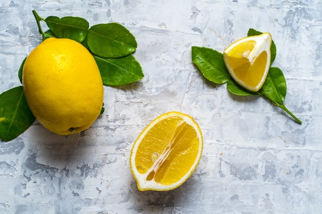 Flache Lage der rohen frischen Zitronenfrucht und der orange Frucht auf grauem Hintergrund- und Kopienraum