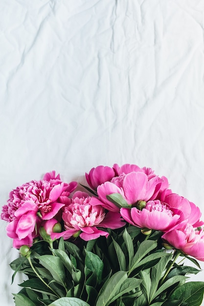 Flache Lage, Draufsicht auf rosa Pfingstrosenblumenstrauß auf weißem Deckenhintergrund