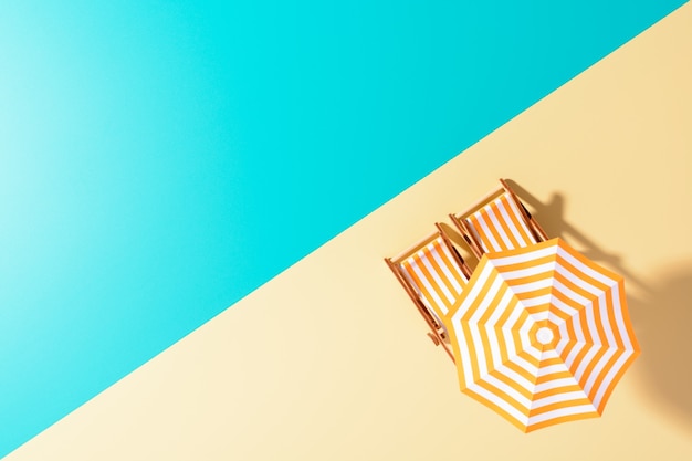 Flache Lage einer komponierten Miniatur des Strandloungebereichs mit Sonnenschirm und Sonnenliegen auf der farbenfrohen Oberfläche.