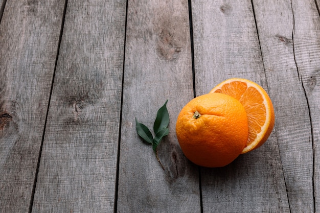 Flache Lage mit frisch reifen geschnittenen Hälften von Orangenfrüchten auf grauem Holzhintergrund.