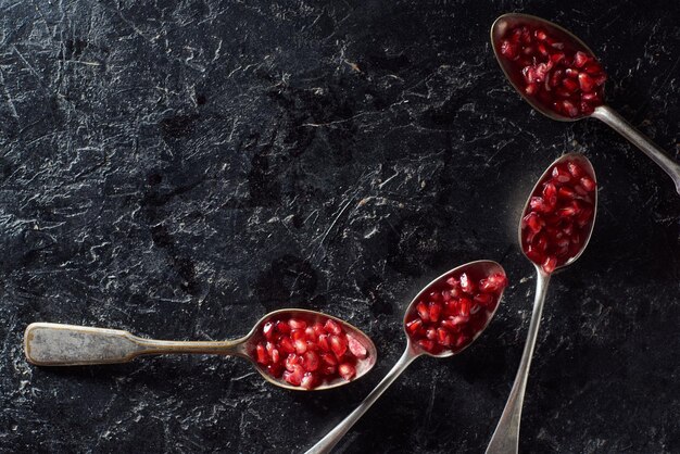 Foto flache lage mit löffeln granatsamen auf strukturiertem hintergrund