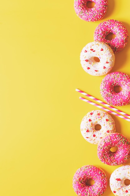 Flache Lage mit rosa Donuts oder Donuts-Muster vertikal auf gelbem Hintergrund