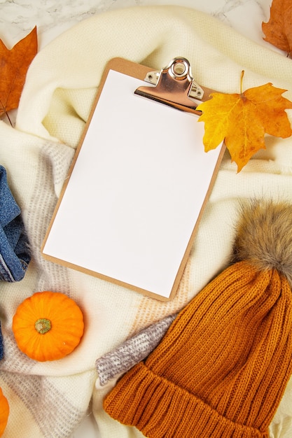 Flache Laienherbstzusammensetzung mit Herbstlaub, Kürbisen, Jeans und einem warmen Wollschal und einer Mütze