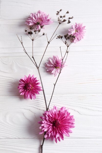 Flache Laienkomposition mit schönen Blumen auf weißem Holztisch