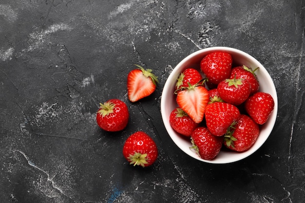Flache Laienzusammensetzung mit reifen roten Erdbeeren auf schwarzem Hintergrund