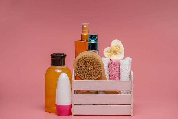 Foto flache laienzusammensetzung mit spa-kosmetik und handtuch auf rosa hintergrund