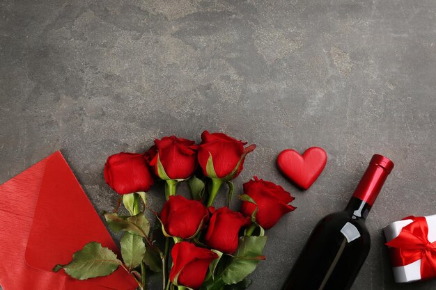 Flache Lay-Komposition mit schönen roten Rosen und einer Flasche Wein auf grauem Hintergrund Platz für Text Valentine39s Day Celebration