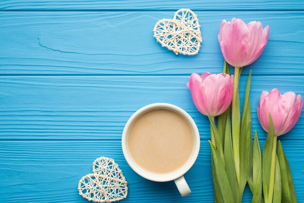 Flache Nahaufnahme Draufsicht Overhead-Foto von schönen modischen pastellfarbenen Tulpen mit Rattan-Herzen einzeln auf hellblauem Holztisch