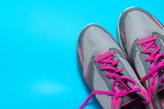 Flache Schuhe der Sportlage legen rosa auf blauem Hintergrund mit copyspace ab.