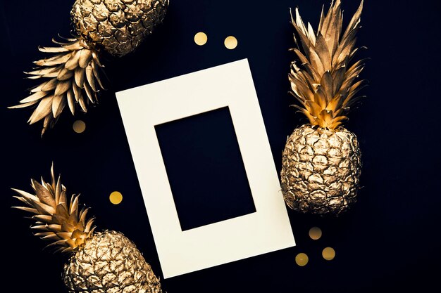 Flache tropische goldene Ananas und Konfetti auf dunklem Hintergrund