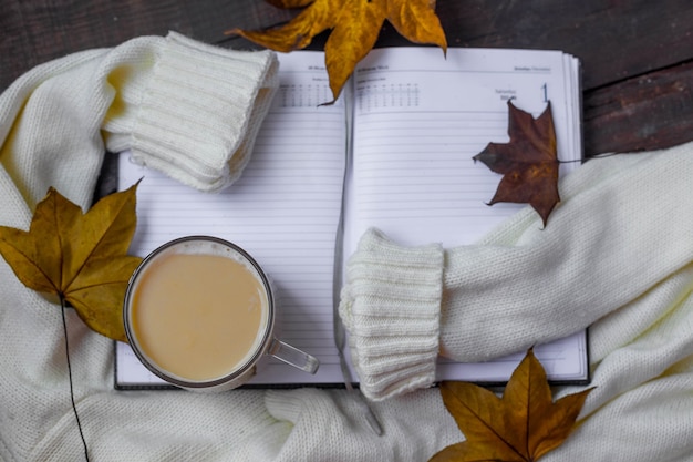 Flache Zusammensetzung des Herbstlaubs mit warmem Pullover und Tasse Kaffee.