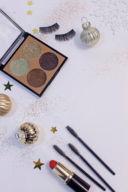 Flache Zusammensetzung mit Make-up-Produkten und Weihnachtsdekor auf weißem Hintergrund. Vorlage für Design, Ansicht von oben Flache Kopienraum.