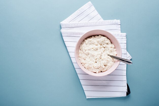 Flacher Brei in Schüssel mit Löffel auf Serviette auf Blau mit Kopierraum legen