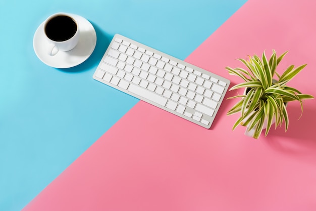Foto flacher büroschreibtisch des modernen arbeitsplatzes mit laptop auf blauem und rosa tisch,