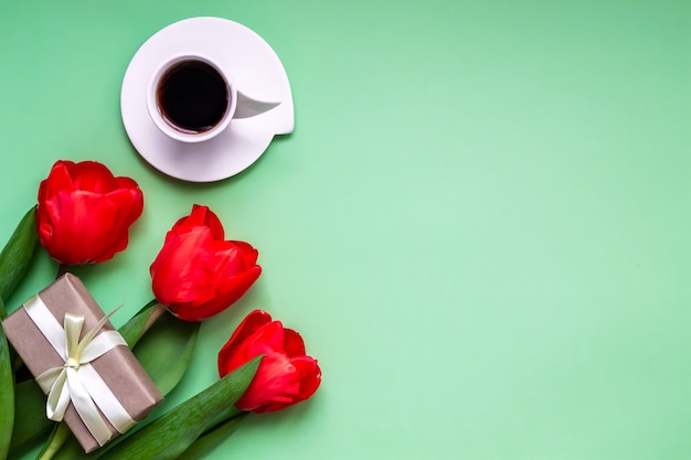 Flacher Grußhintergrund Kaffee in einer Tasse rote Tulpen auf grünem Hintergrund mit Platz für Text