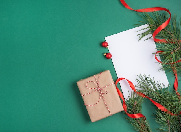 Flacher lag Weihnachtshintergrund mit grünem Baum, leerem Blatt Papier, Spielzeug und Geschenk. Draufsicht