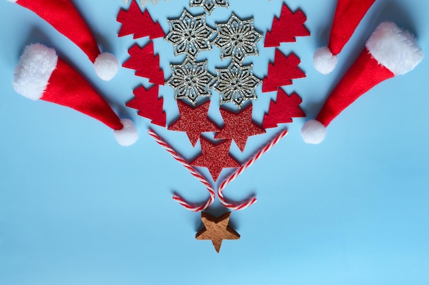 Flacher Weihnachtsbaum aus bunten Dekorationen vor blauem Hintergrund. Ansicht von oben. Karte