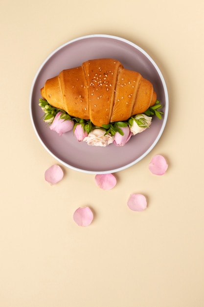 Foto flaches croissant mit blumen auf dem teller