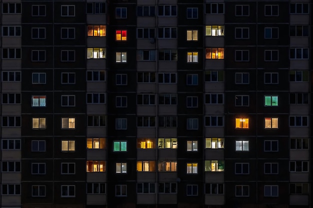 Flaches Nachtpanorama mit mehrfarbigem Lächelngesichtslicht in Fenstern von mehrstöckigen Gebäuden