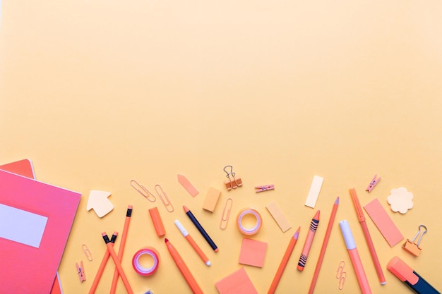 Flaches Schulmaterial auf orangefarbenem Hintergrund