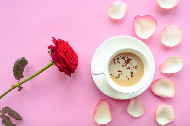 Flachgestelltes Foto mit Kaffeetasse und roter Rose auf rosa Hintergrund Valentinstag oder Hochzeits-Grüßkarte Liebeskonzept