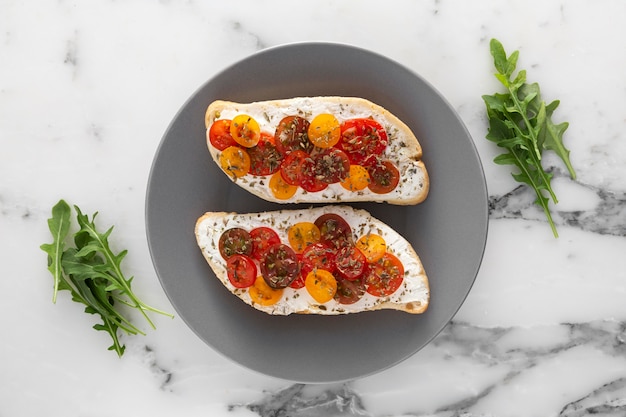 Fladenbrot mit Frischkäse und Kirschtomaten auf Teller legen