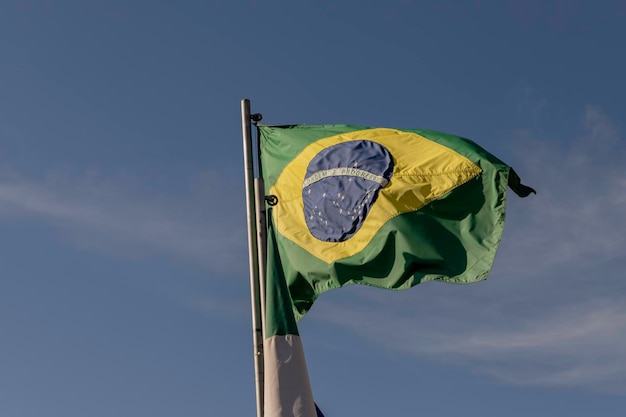 Flagge Brasiliens flattert im Wind mit blauem Himmel im Hintergrund Selektiver Fokus