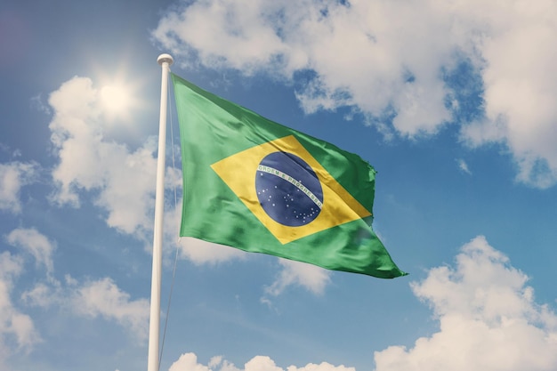 Flagge Brasiliens, nationales Symbol weht gegen bewölkten, blauen Himmel, sonniger Tag