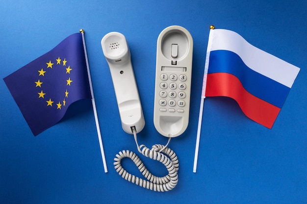 Flagge der Europäischen Union Russland und ein altes Kabeltelefon auf blauem Hintergrund Konzept zum Thema Telefongespräche