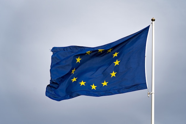 Flagge der Europäischen Union weht im Wind am Fahnenmast in Zeitlupe auf bewölktem Himmelshintergrund. Hochwertiges FullHD-Filmmaterial