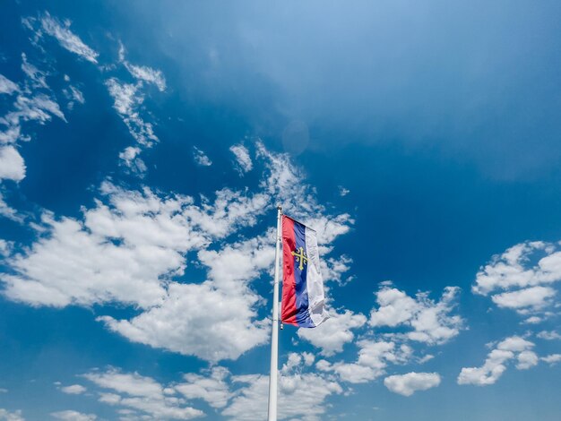 Flagge der serbischen orthodoxen Kirche auf einem Fahnenmast gegen einen bewölkten Himmel