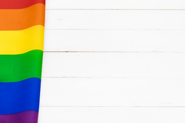 Flagge des homosexuellen Stolzes auf Holztisch