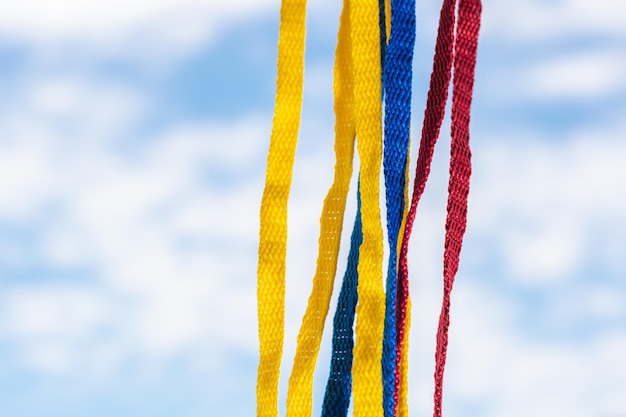 Flagge Kolumbiens mit Schnürsenkeln, die auf einem Hintergrund des Himmels und der Wolken hängen