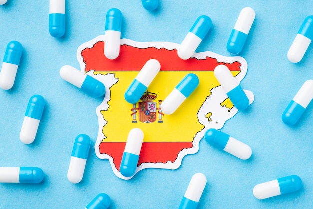 Flagge Spaniens mit vielen Kapseln oben als Symbol für den schlechten Gesundheitszustand der Bürger