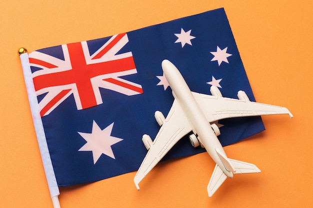 Flagge und Spielzeugflugzeug auf farbigem Hintergrund ein Konzept zum Thema Reisen nach Australien