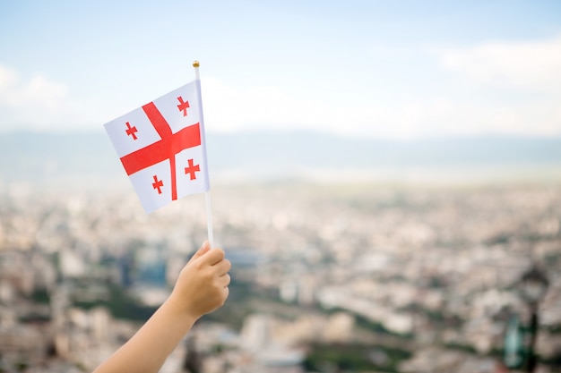 Flagge von Georgia in der Hand eines Kindes gegen den Himmel