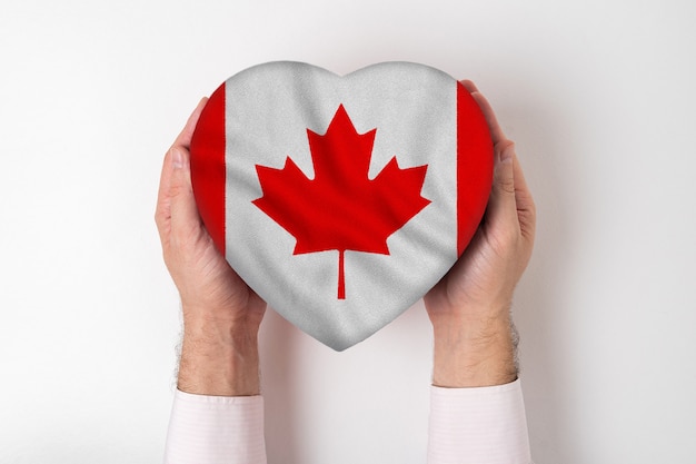 Flagge von Kanada auf einem Herzen formte Kasten in männliche Hände.