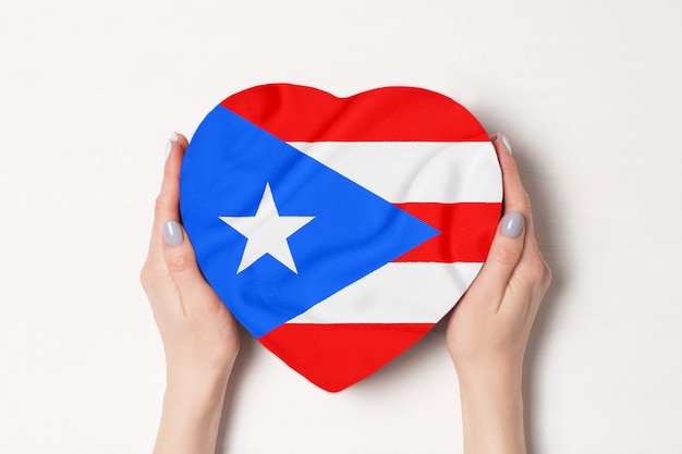 Flagge von Puerto Rico auf einem Herzen formte Kasten in weibliche Hände