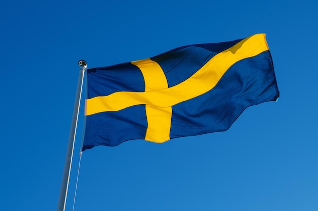 Flagge von Schweden gegen den nationalen patriotischen Hintergrund des blauen Himmels