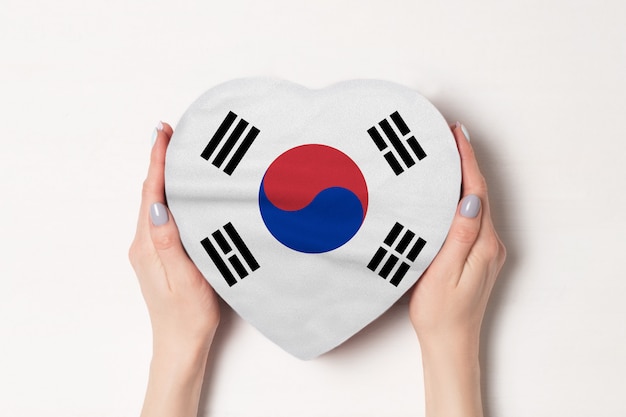 Flagge von Südkorea auf einem Herzen formte Kasten in weibliche Hände.