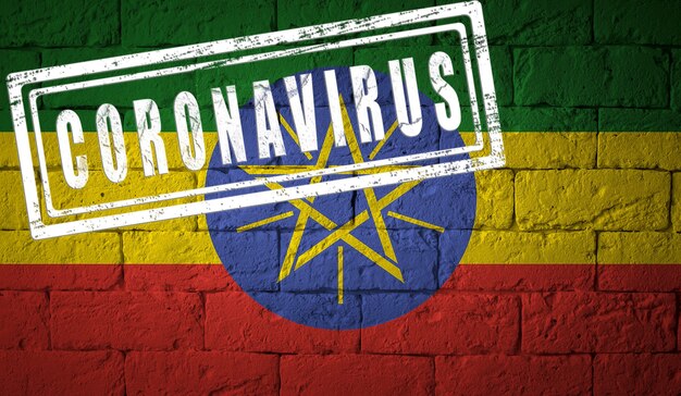 Flagge von Äthiopien auf Backsteinmauerbeschaffenheit. gestempelt mit Coronavirus. Konzept des Corona-Virus. Am Rande einer COVID-19- oder 2019-nCoV-Pandemie. Neuartiger chinesischer Coronavirus-Ausbruch