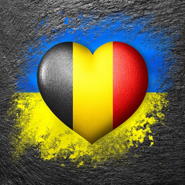 Flaggen der Ukraine und Belgiens Flaggenherz auf dem Hintergrund der auf einen Stein gemalten Flagge der Ukraine