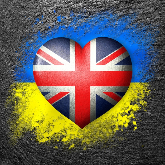 Flaggen der Ukraine und Großbritanniens Flaggenherz auf dem Hintergrund der Flagge der Ukraine malen auf Stein