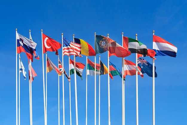 Flaggen verschiedener Länder der Welt fladdern im Wind vor einem klaren blauen Himmel