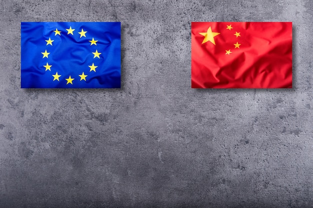 Flaggen von China und der Europäischen Union auf konkretem Hintergrund.