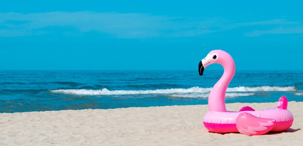 Flamingo inflável em uma praia arenosa