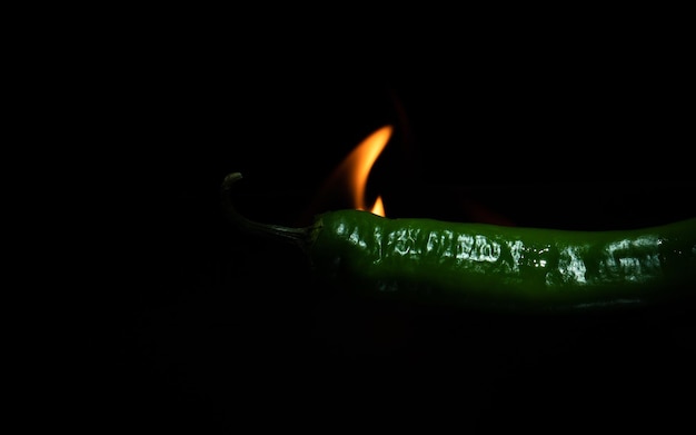 Flammende grüne Chilischote hautnah auf dunklem Hintergrund