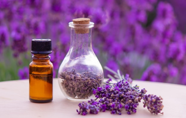 Flasche ätherisches Lavendelöl auf Holztisch und Blumenfeldhintergrund